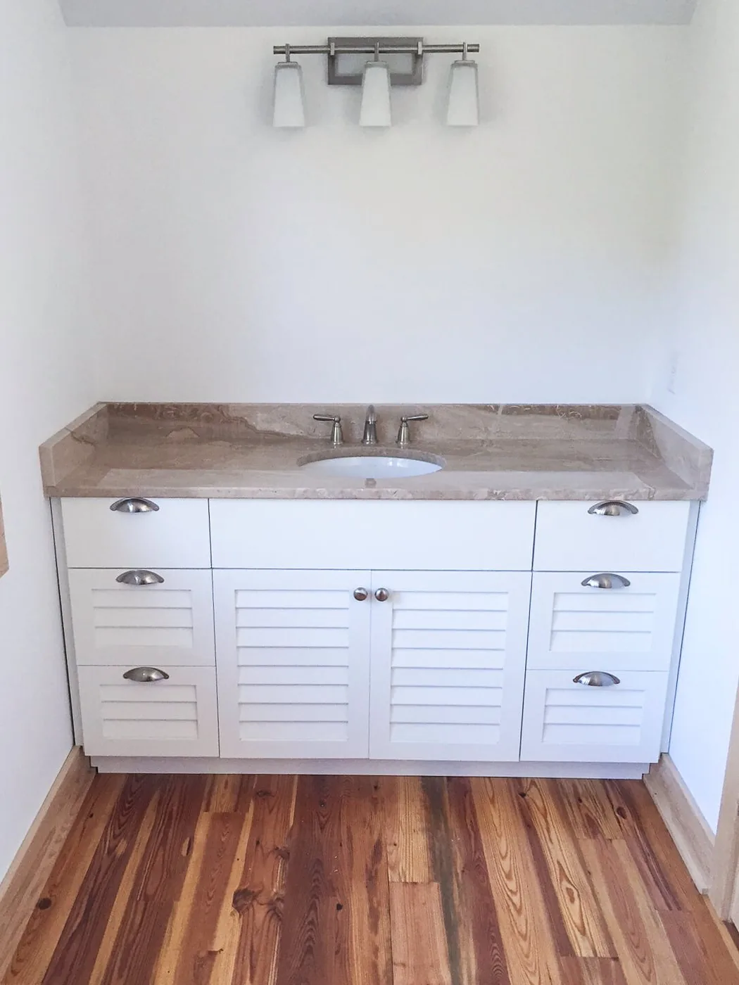 A freestanding FFT vanity with louvered doors and a stone top