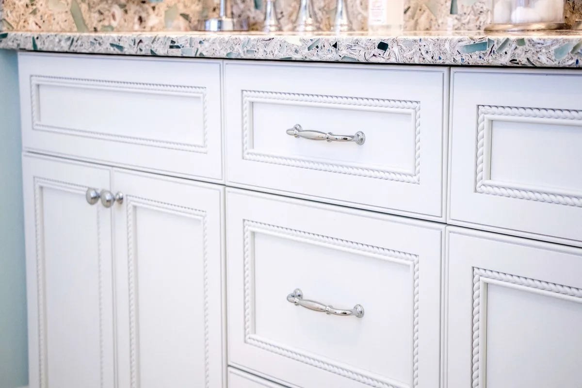 A bathroom vanity run with beaded detail and a stone top