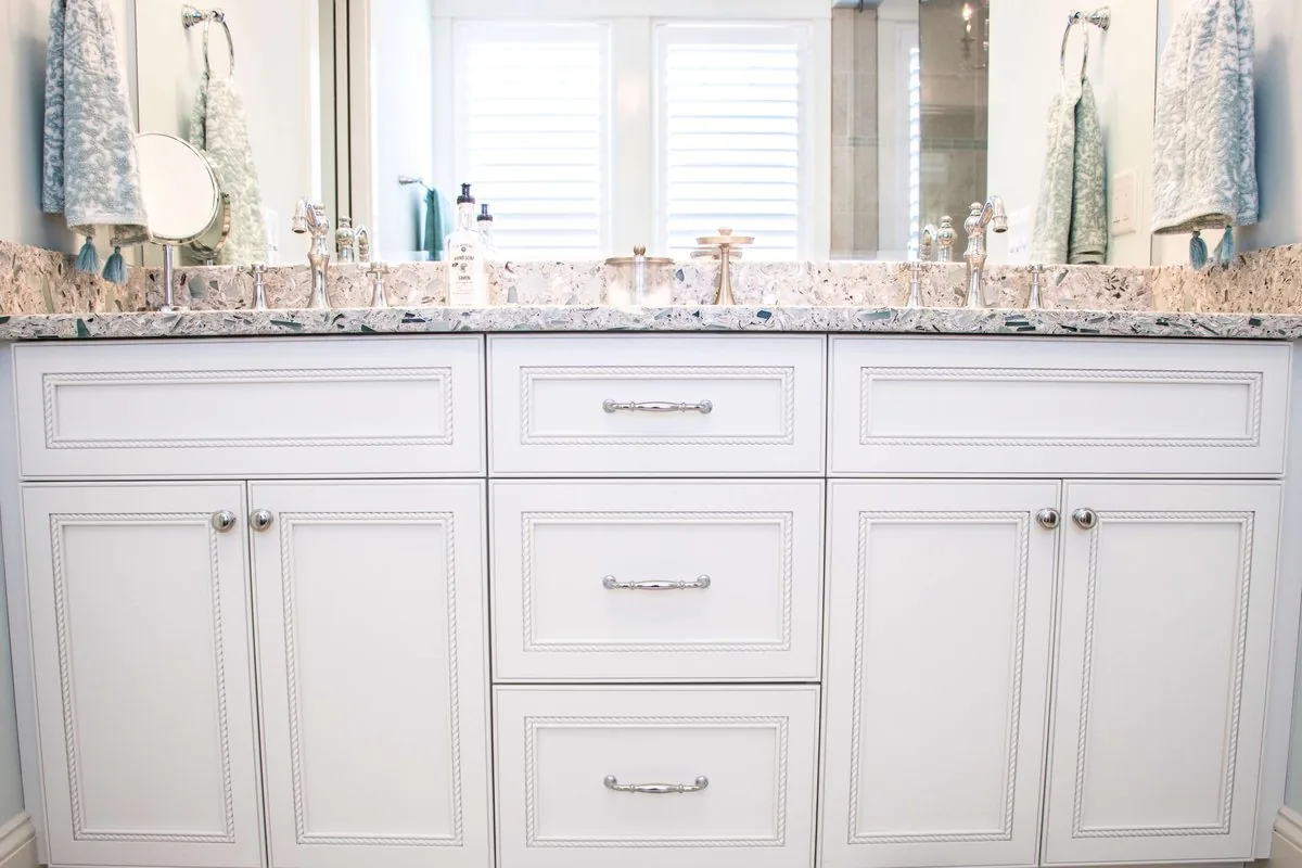 A double vanity with mirrors and a granite counter