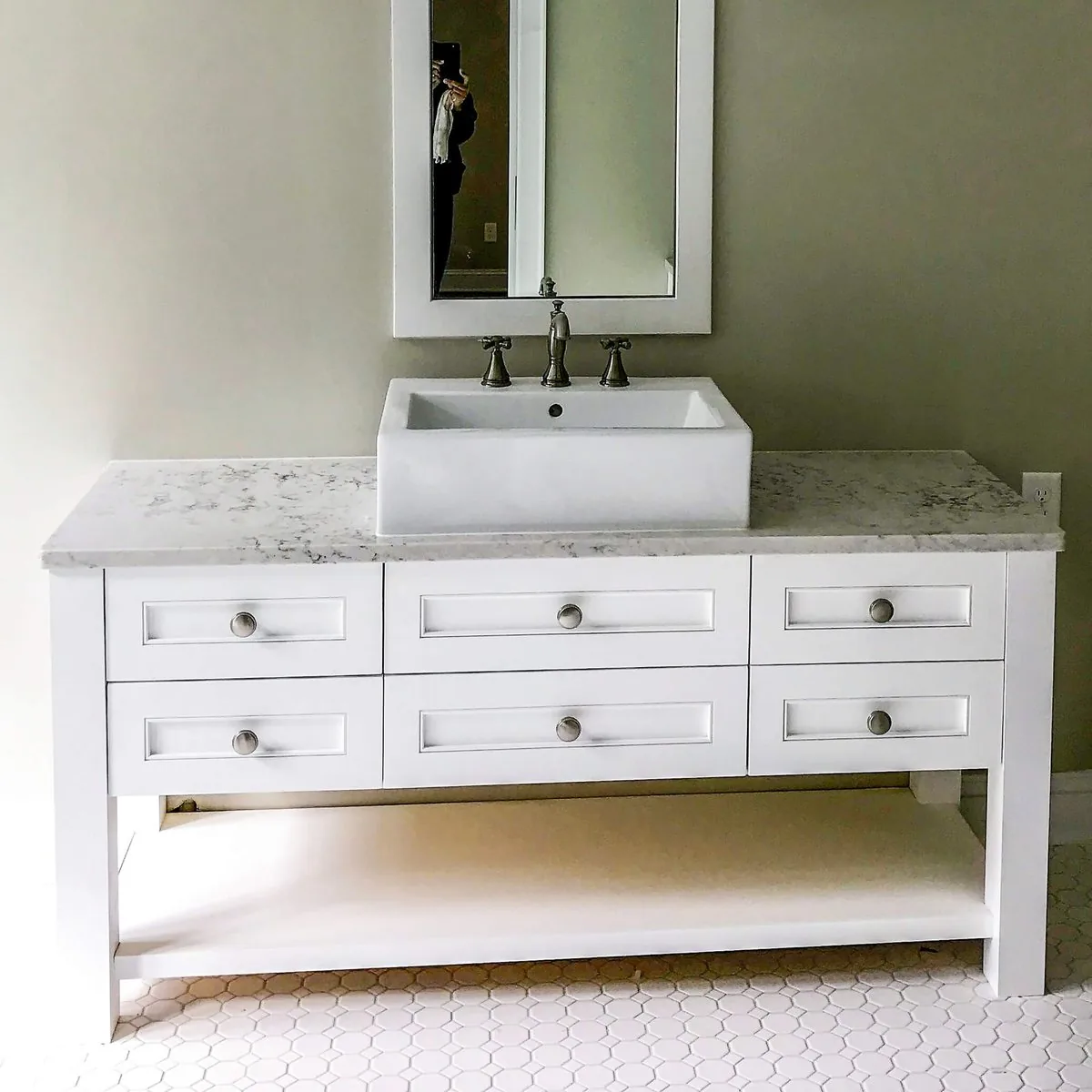 A freestanding vanity with an open lower shelf and a marble top