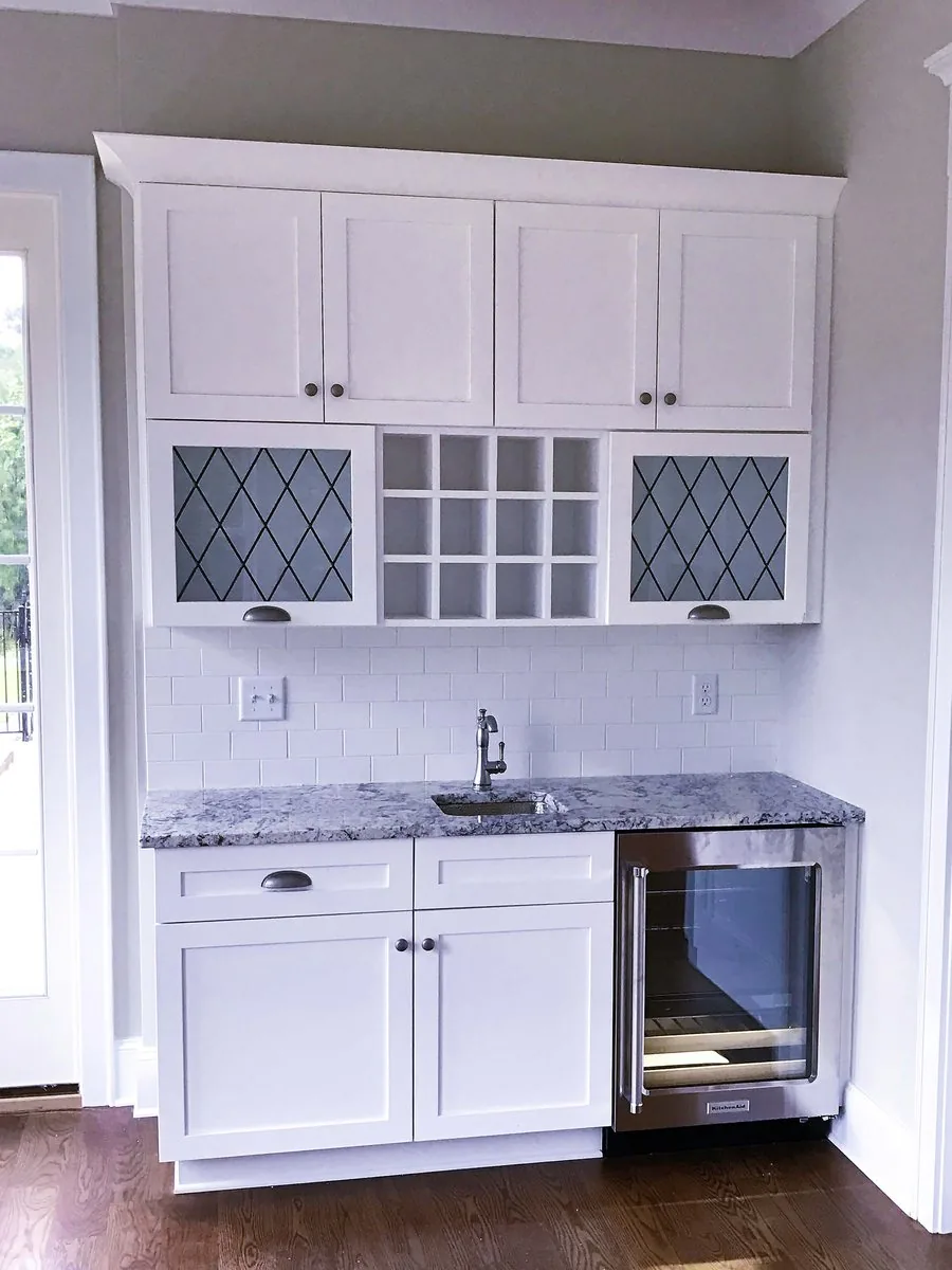 A wet bar with leaded glass uppers and a beverage cooler