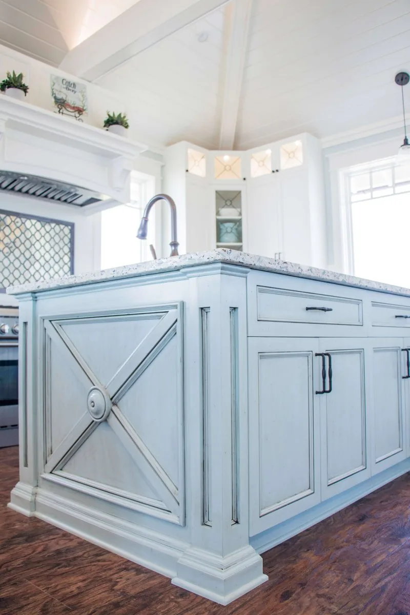 A painted kitchen island with an X detail panel and stone top