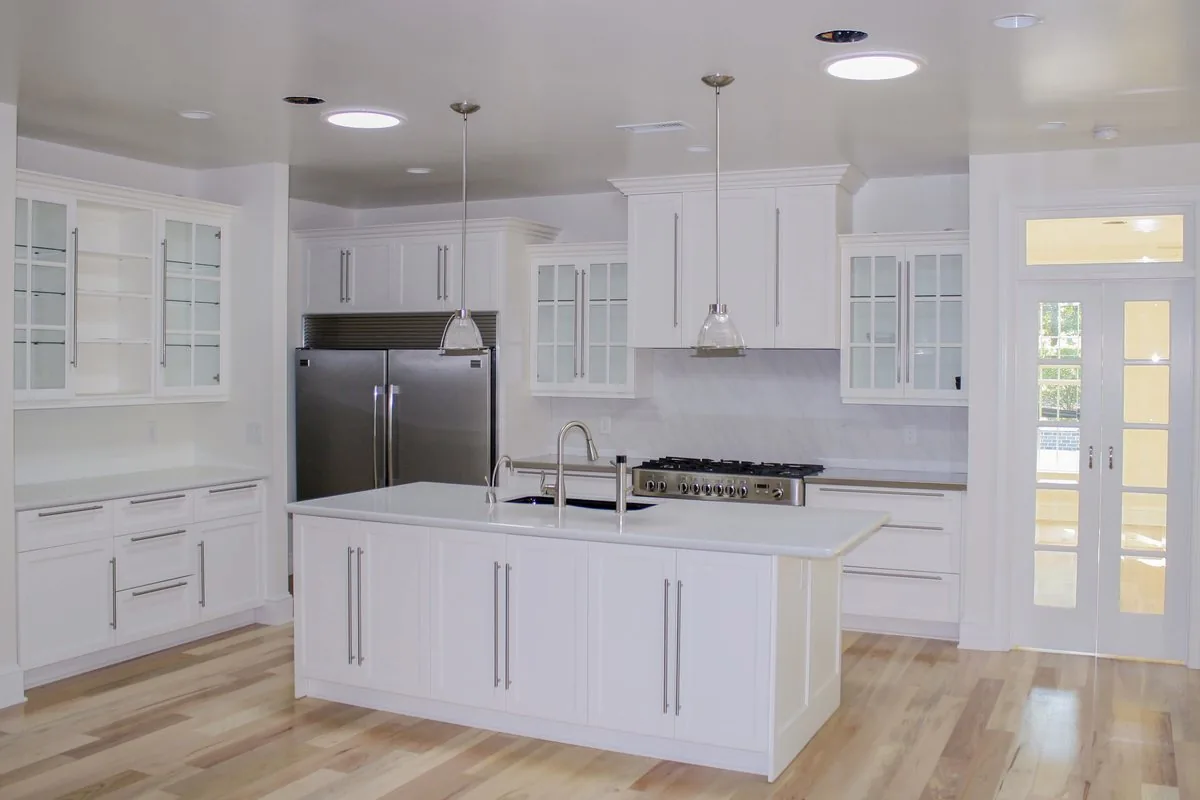 A white kitchen with glass front uppers and a wide island