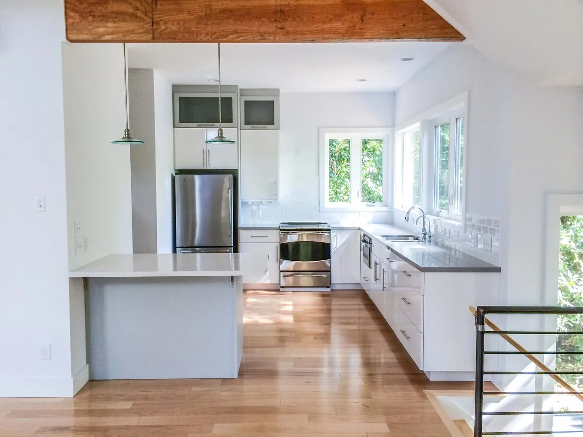 A kitchen with an exposed beam, painted cabinetry, and a long island