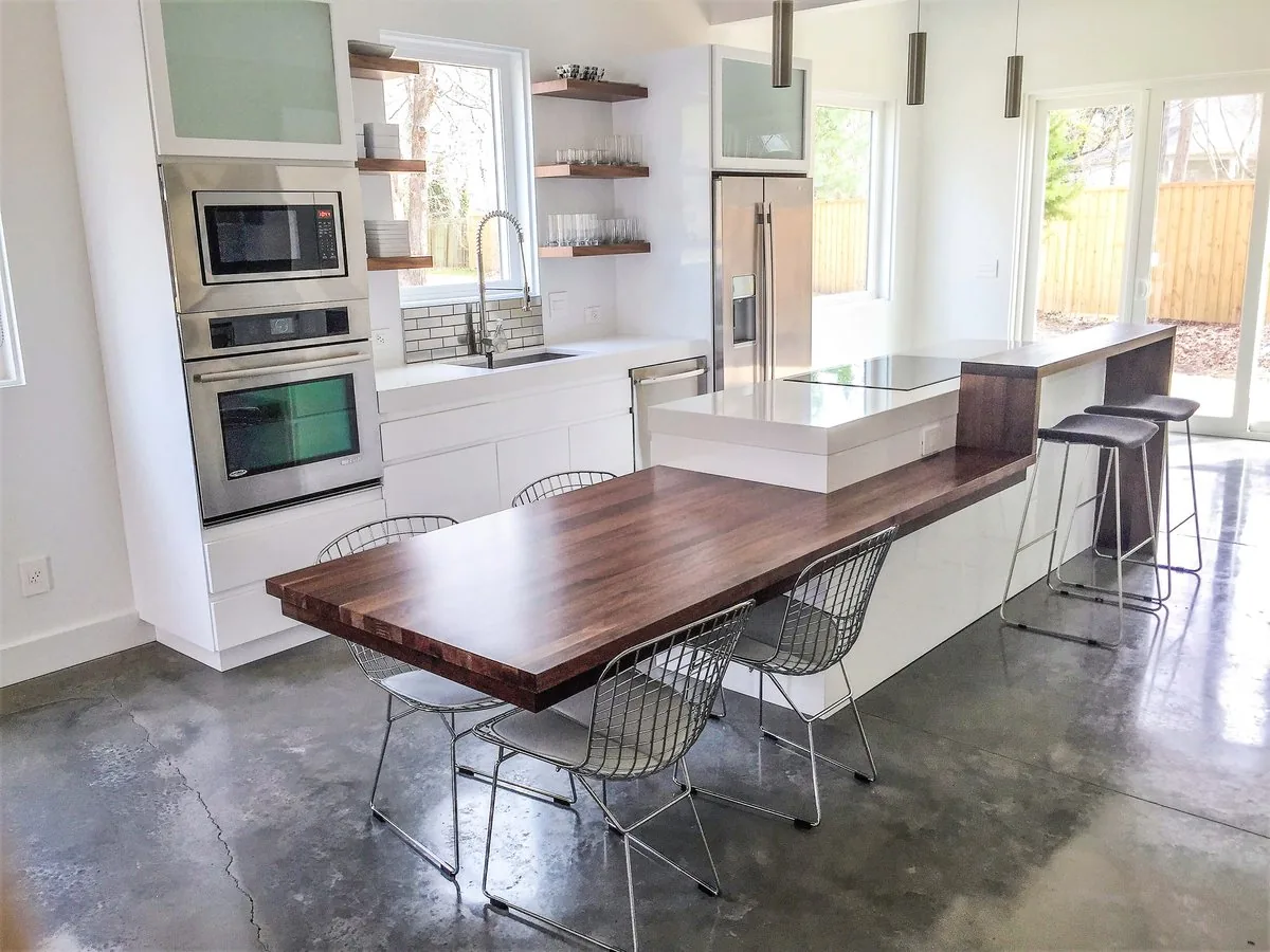 A kitchen with a walnut table extending from the island