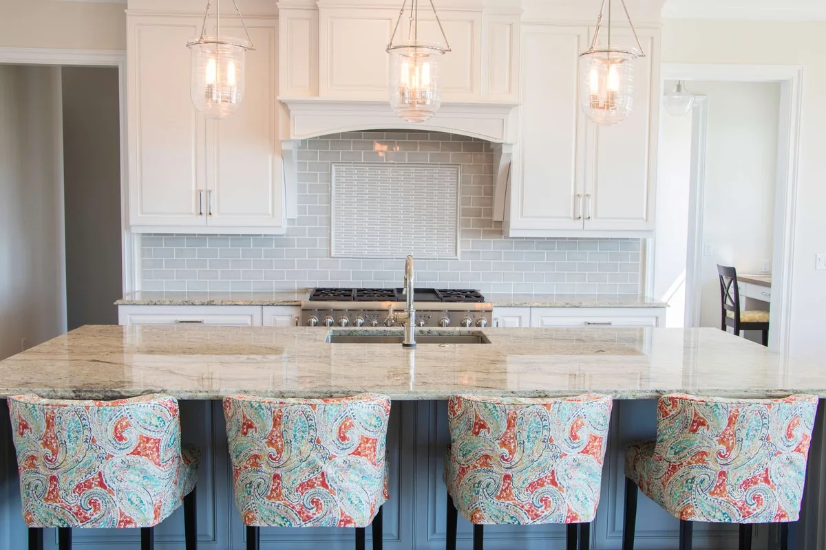 A kitchen with a tiled hood surround and a granite bar seat island
